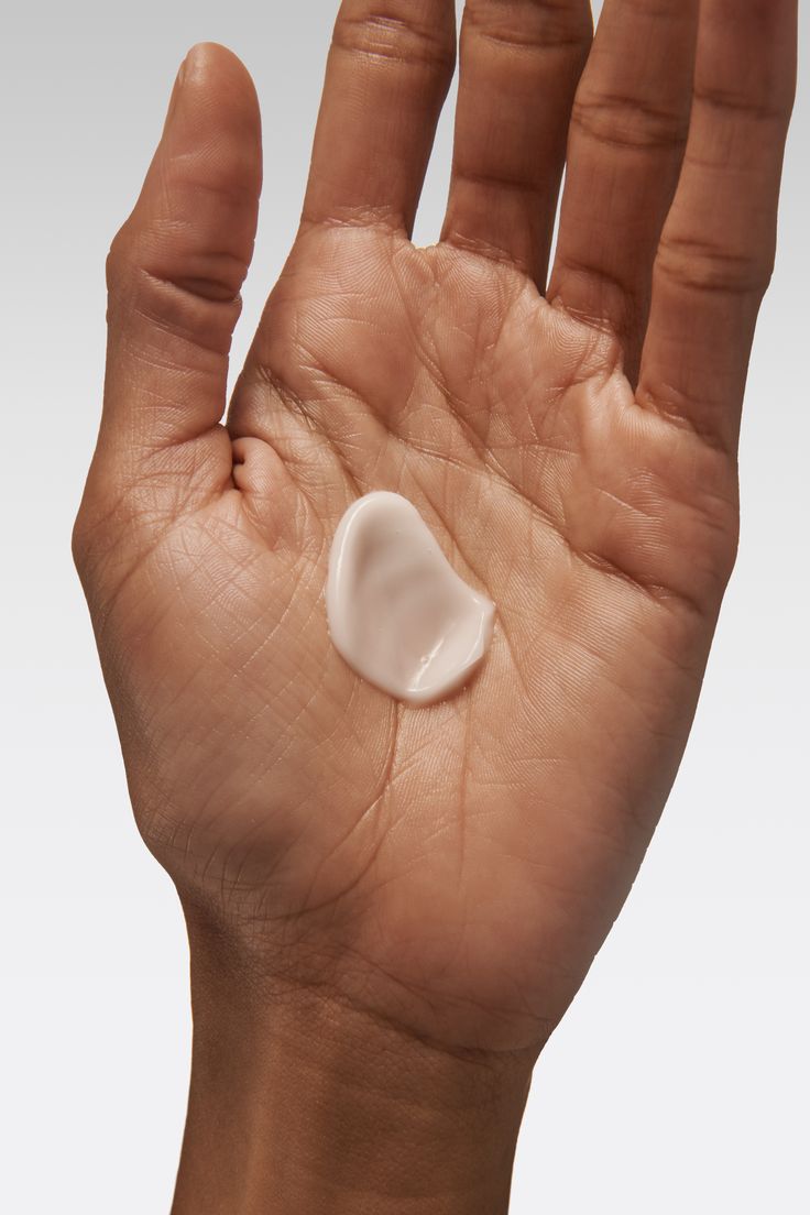 Hand holding a small white object against a neutral background