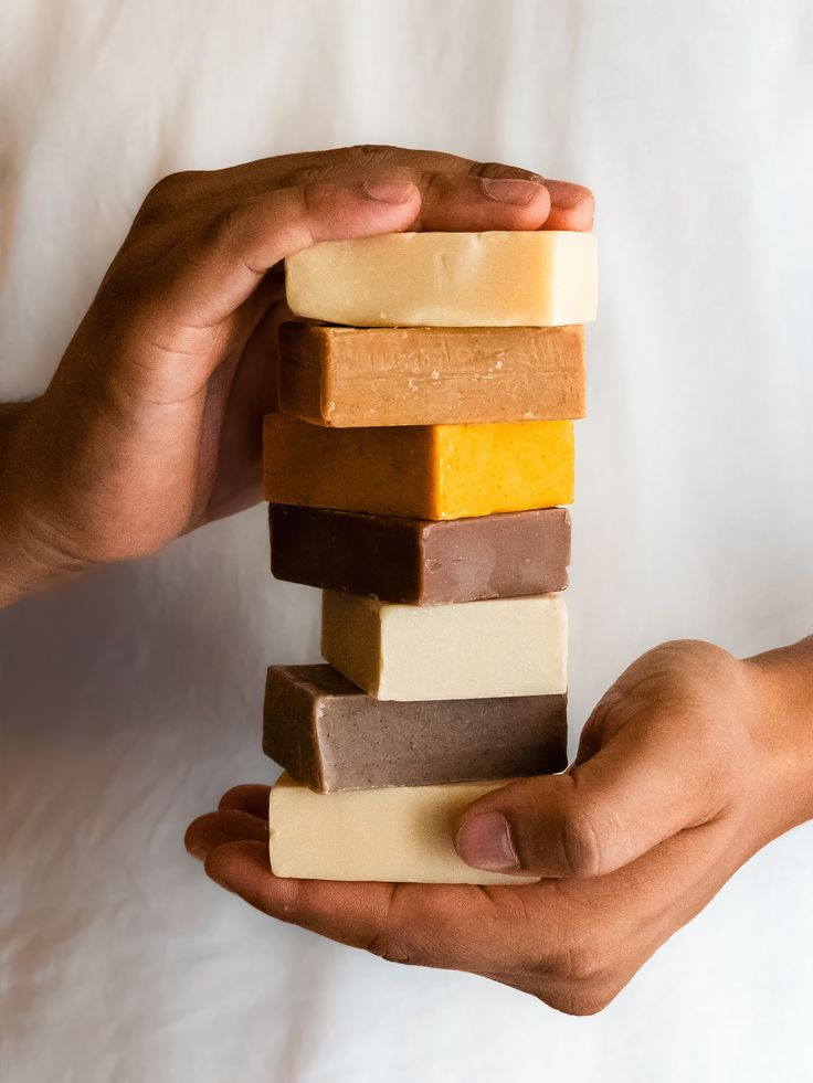 Stack of handmade soap bars held by a person against a white background