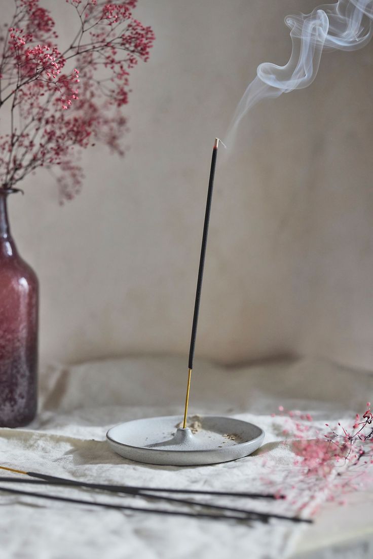 Incense stick with smoke on a white plate with a blurred background