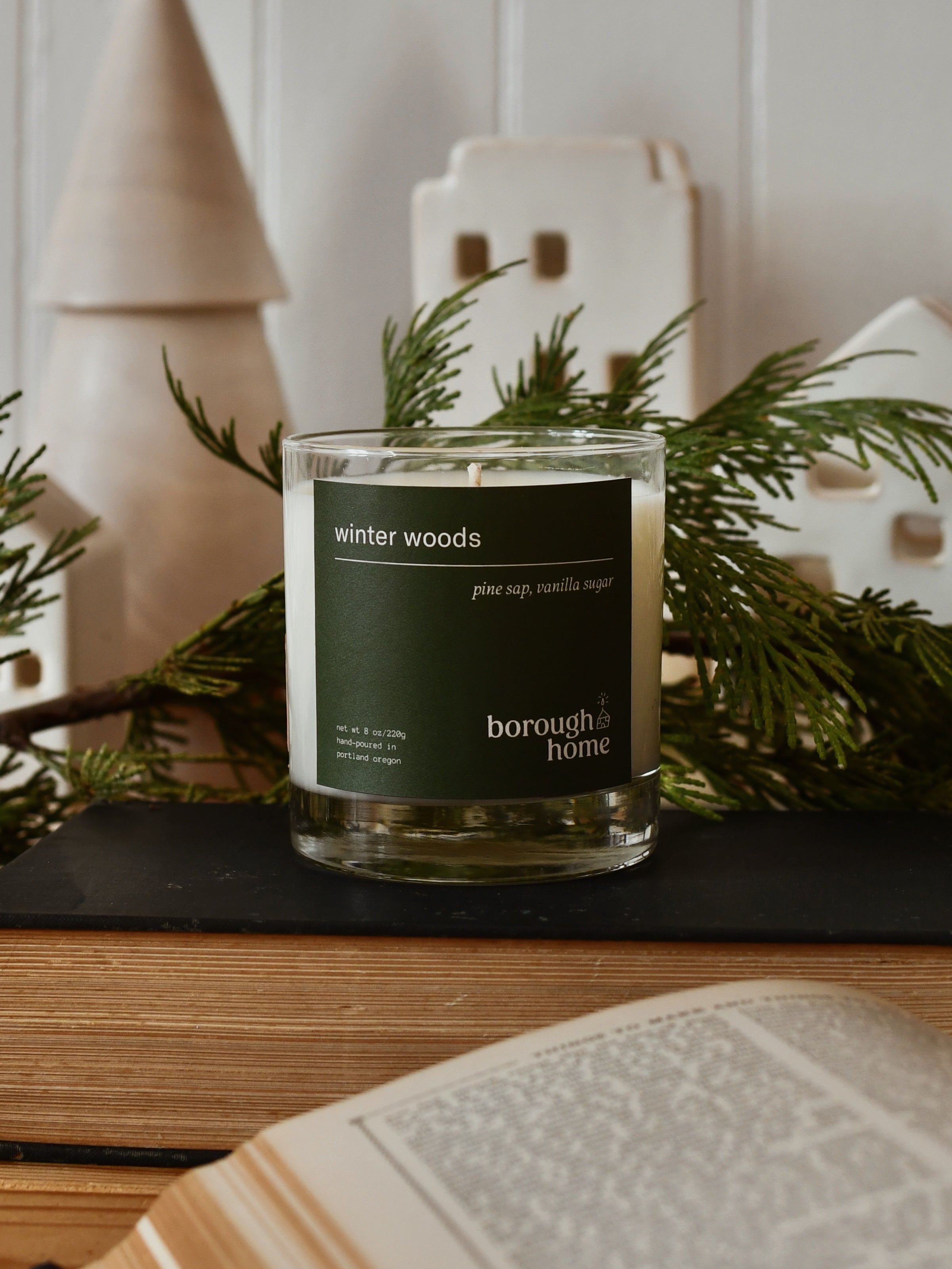 Winter Woods candle, front view with pine boughs and holiday decor.