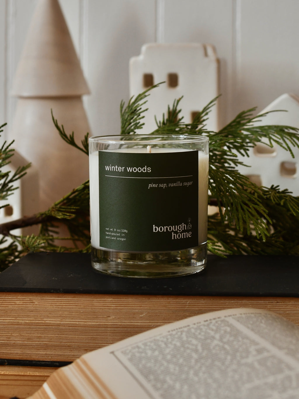 Winter Woods candle, front view with pine boughs and holiday decor.